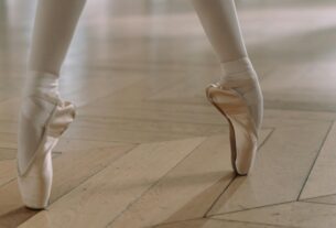 Close-up of a ballerina's feet in pointe shoes, showcasing grace and balance on a wooden floor.