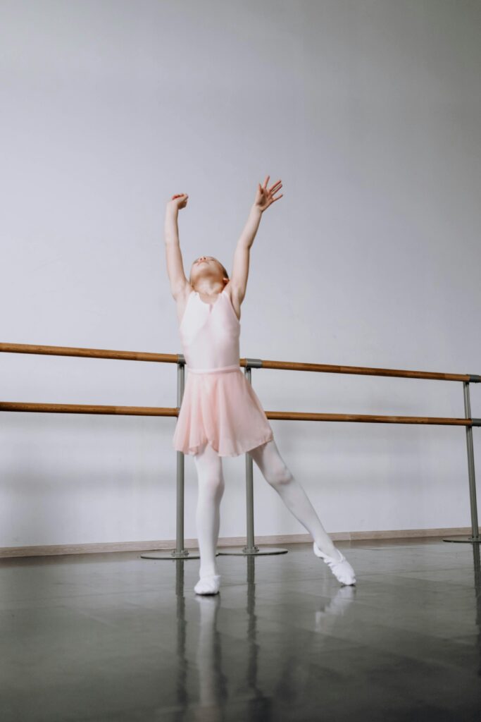 pexels-photo-6717377-6717377 A young girl in a pink tutu gracefully stretches in a ballet studio.